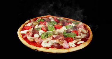 Pişirme işlemi sırasında pizza, siyah arka planda izole edilmiş. Stüdyo çekimlerinde yemek pişirme zamanı, erimiş peynir ve taze malzemeler görülüyor. Yemek, yemek ve restoran kavramları için mükemmel..