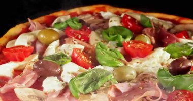 Pişirme işlemi sırasında pizza, siyah arka planda izole edilmiş. Stüdyo çekimlerinde yemek pişirme zamanı, erimiş peynir ve taze malzemeler görülüyor. Yemek, yemek ve restoran kavramları için mükemmel..