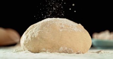 Siyah zemin üzerinde izole edilmiş mayalanmış hamur somununun statik görüntüsü. Süper yavaş çekimde un düşüyor. 1000 fps. Pişirme, zanaatkar ekmek yapma ve hamur hazırlama kavramı.