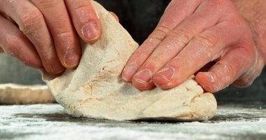 Fırıncının elleri yoğurur ve yeni yükselen hamuru uzatır. Detaylı doku ve esneklik sinemada görülebilir. Maya hamuru hazırlama ve geleneksel pişirme süreci kavramı.