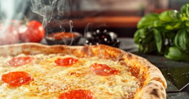 Erimiş peynirli, sıcak ve iştah açıcı ışıkta altın hamurlu yeni pişmiş bir pizzanın yakın çekimi. Zengin dokusu ve davetkar sunumu olan klasik konforlu yiyecek konsepti.