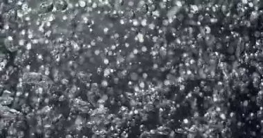 Aşırı yavaş hareket eden su, yükselen hava kabarcıkları ve parıldayan ışık parçacıkları dinamik hareket ve siyah ve beyaz tonlarıyla soyut bir sualtı makro arkaplanı oluşturur..