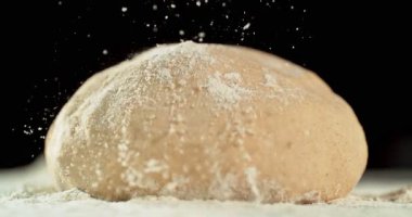 Siyah zemin üzerinde izole edilmiş mayalanmış hamur somununun statik görüntüsü. Süper yavaş çekimde un düşüyor. 1000 fps. Pişirme, zanaatkar ekmek yapma ve hamur hazırlama kavramı.