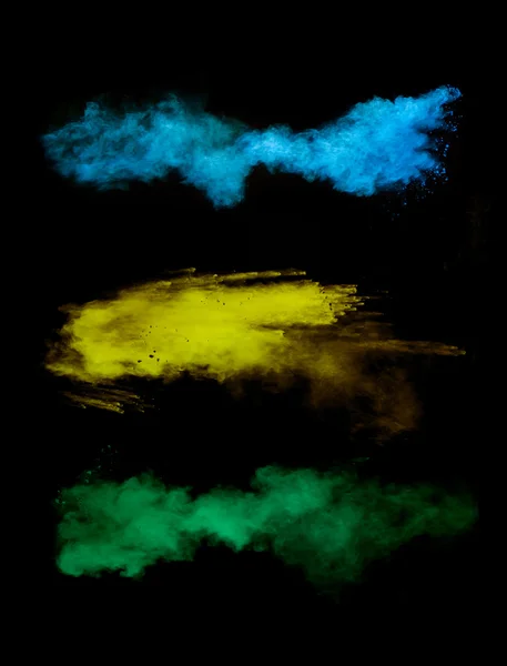 Замораживание движения цветных пылевых взрывов на черном фоне — стоковое фото