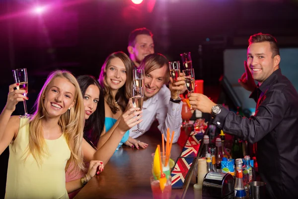 Happy young people clinking with champagne in nightclub. — Stock Photo, Image