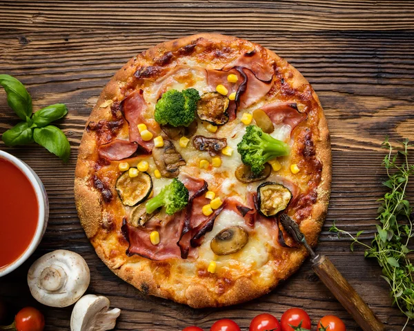 Pyszne włoskie pizzy serwowane na drewnianym stole — Zdjęcie stockowe