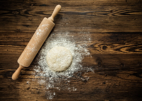 Yeast dough on table with rolling pin