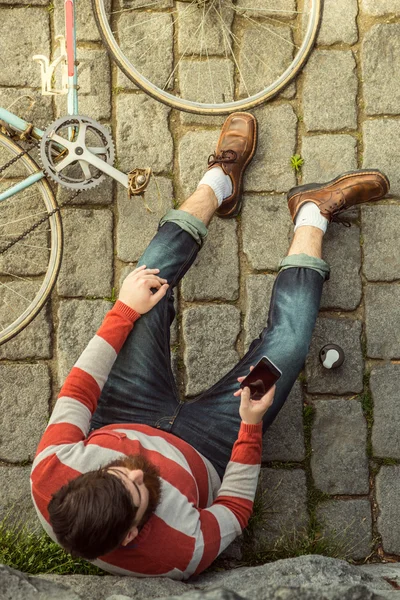 Hipster młody człowiek siedzi i przy użyciu telefonów komórkowych — Zdjęcie stockowe