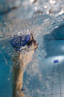 Genç adam havuzda yüzüyor.