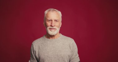 Gülümseyen, yakışıklı, son sınıf öğrencisi. Öpüşmeyi bitiriyor, kameraya bakıyor. Kırmızı arka planda yalnız poz veren mutlu erkek model. Aşk, pozitif duygular konsepti