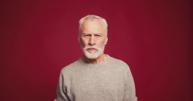 Üzgün, üzgün, ağlayan, stresten ağlayan, kırmızı arka planda izole edilmiş bir sorun. Sinirli, emekli bir erkek kameraya bakıyor. Duygular konsepti