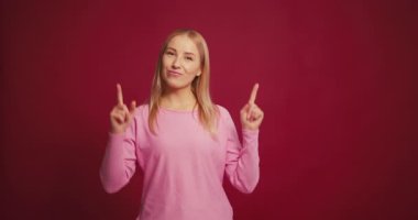 Mutlu, orta yaşlı bir kadın parmağını kaldırmış, kameraya bakıyor, kırmızı arka planda izole bir şekilde poz veriyor. Stüdyoda izole edilmiş güzel bir kadın. Reklam, alışveriş konsepti