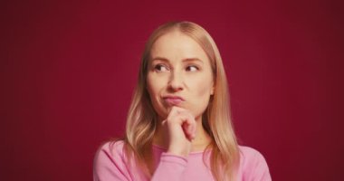 Endişeli sarışın kadın kırmızı arka planda izole edilme sorunu yaşayarak başka tarafa bakıyor ve endişeleniyor. Sorun kavramı