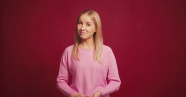 Gülümseyen sarışın kadın kırmızı arka planda baş parmağını kaldırarak evet diyor. İyi seçim, alışveriş konsepti.