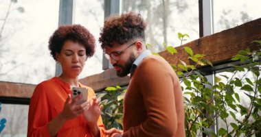 Modern ofiste, akıllı telefon kullanarak projeyi tartışan iki meslektaş. Çevrimiçi teknoloji kavramı