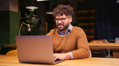 Gülümseyen mutlu iş adamı, modern iş birliğinde dizüstü bilgisayarda çalışıyor. Kopya yazarı klavyeye yazı yazıyor. Çevrimiçi teknoloji kavramı