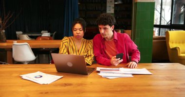 Profesyonel iş arkadaşları iş yerinde oturuyor, dizüstü bilgisayar planlama projesini kullanıyor, modern ofiste birlikte çalışıyorlar. Takım çalışması konsepti