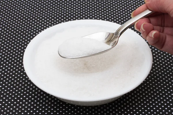 Біла миска, наповнена цукром з ложкою на чорно-білому р — стокове фото