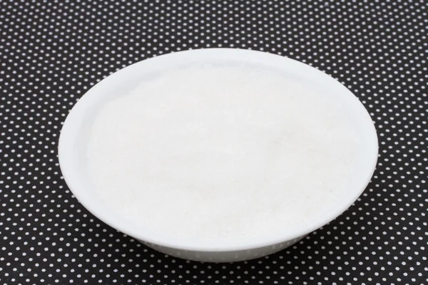 Ciotola bianca riempita di zucchero su un retro a pois in bianco e nero — Foto Stock