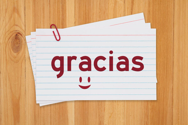 Language flashcards with gracias message on white paper index cards on wood desk