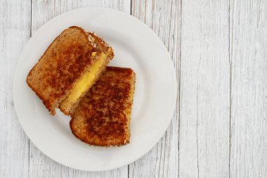 Izgara peynirli ve kepekli sandviç, yıpranmış bir tabakta.