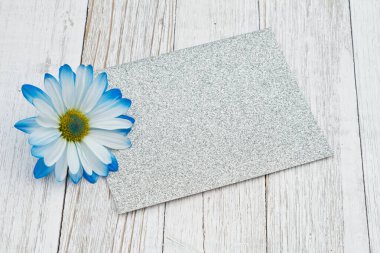 Silinmiş ahşap masadaki çiçekli boş gümüş parıltılı tebrik kartı.