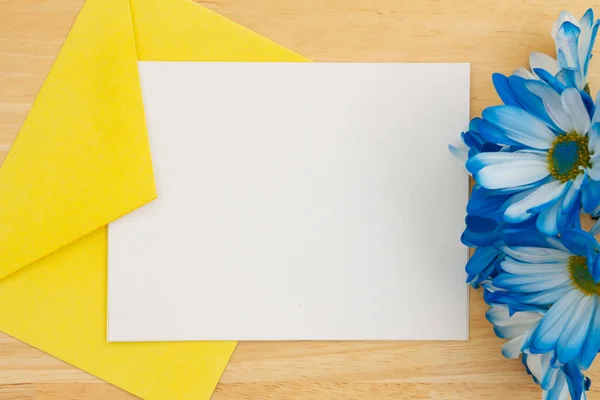 白色空白贺卡 黄色信封 蓝色雏菊在木桌上 — 图库照片