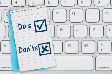 Dos and Donts çevrimiçi gramer iletiniz için gri klavyeye mavi not defteri gönderir