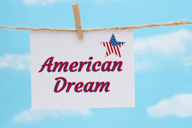 Amerikan Rüyası beyaz tebrik kartı ve açık mavi gökyüzünde Amerikan bayrağı asılı.