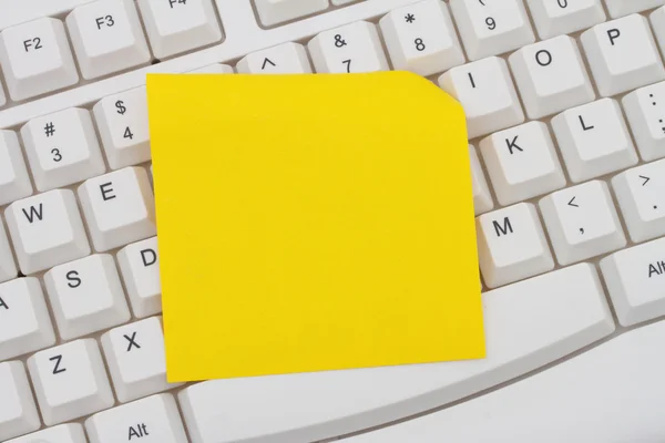 Teclado de ordenador con una nota adhesiva en blanco amarillo —  Fotos de Stock