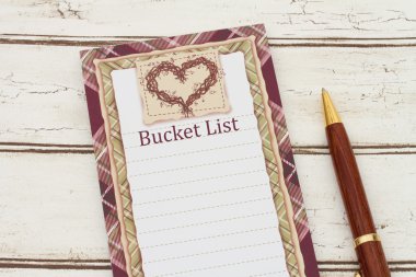 A notepad and pen on weathered wood background with text Bucket  clipart