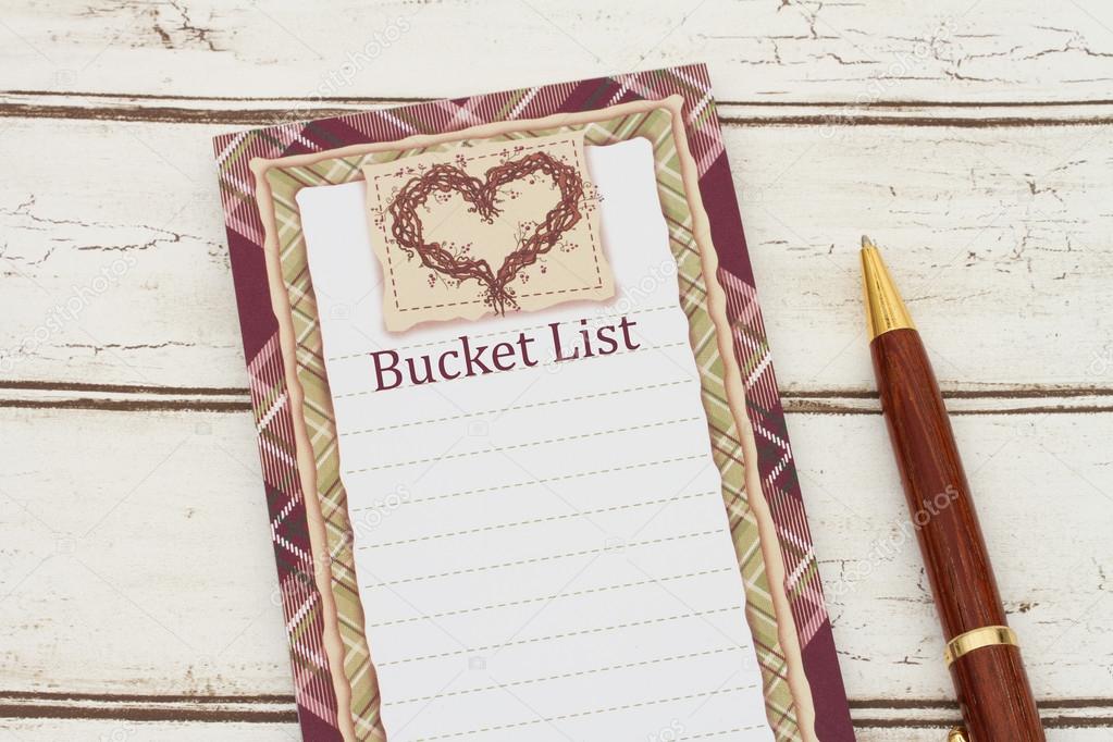 A notepad and pen on weathered wood background with text Bucket 