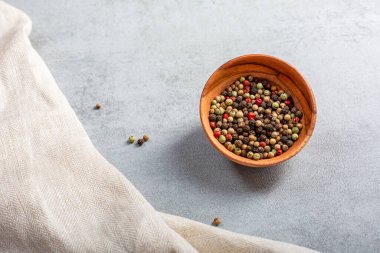 Düz ahşap kase, gri arka planda çok renkli biber karışımı ve metin için fotokopi alanı vardı. İzole edilmiş makro çekim. Yakın plan. Baharat konsepti.