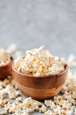 Gri arka planda ahşap bir kasede ev yapımı patlamış mısır.