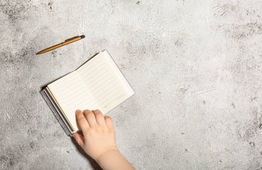 Açık satırlı defterleri ve somut arka planda izole edilmiş kalemi olan bir model.