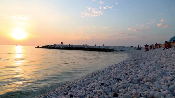 Pôr do sol sobre ondas do mar lavar pedras praia — Vídeo de Stock