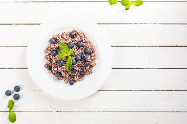 Beyaz ahşap masada servis edilen yaban mersinli leziz risotto.