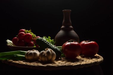 Siyah arka planda sebzelerle dolu bir hayat. Turplar, domatesler, yeşil soğanlar, sarımsak, marul, salatalık.