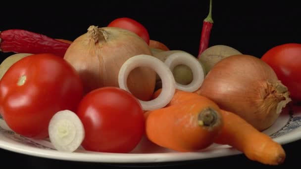 Verduras crudas en un plato. Patatas, cebollas, tomates, zanahorias, pimientos rojos picantes. — Vídeos de Stock