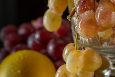 Siyah arkaplanda elmalar ve üzümler.