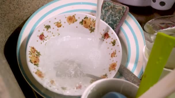 L'acqua si versa in piatti sporchi nel lavandino della cucina — Video Stock