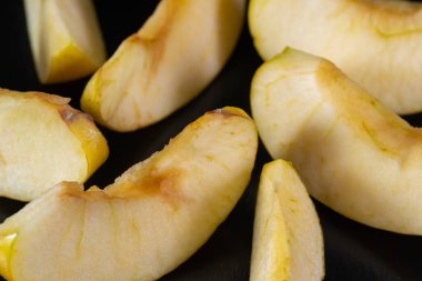 Sarı elma, dilimler halinde, siyah bir arkaplanda..