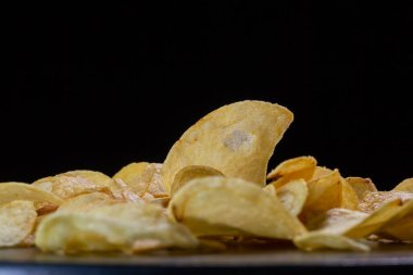 Siyah arka planda patates cipsi. Yakın plan..