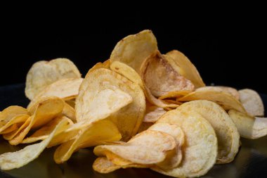 Siyah arka planda patates cipsi. Yakın plan..