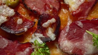 Tütsülenmiş et, domates, zeytin ve bitkilerle ev yapımı pizza..