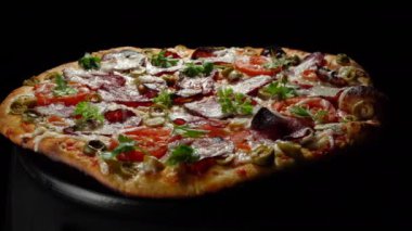 Tütsülenmiş et, domates, zeytin ve bitkilerle ev yapımı pizza..