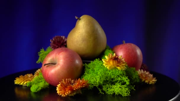 Composition of pears, apples, moss and yellow flowers. — Stock Video