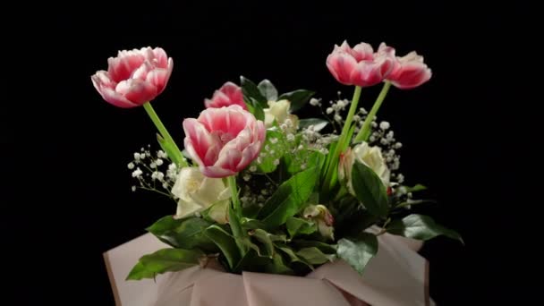 Buquê de flores em um fundo preto. Tulipas vermelhas e brancas e rosas brancas. — Vídeo de Stock