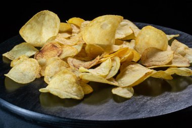 Siyah arka planda patates cipsi. Yakın plan..