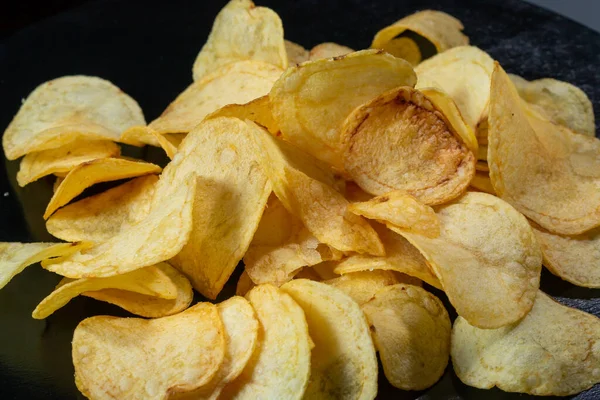 Siyah arka planda patates cipsi. Yakın plan..